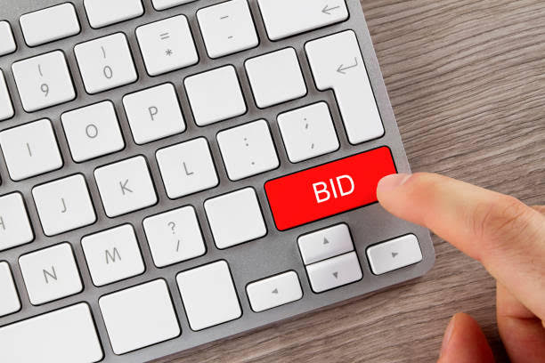 Human finger is pushing 'Bid' button on computer keyboard